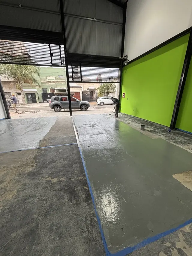 Local comercial en obra con paredes verdes y piso en preparación